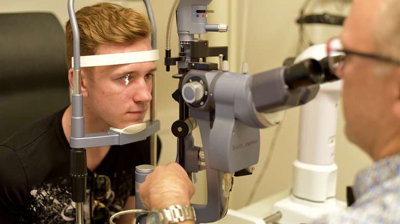 Mann som får synet undersøkt med optisk utstyr